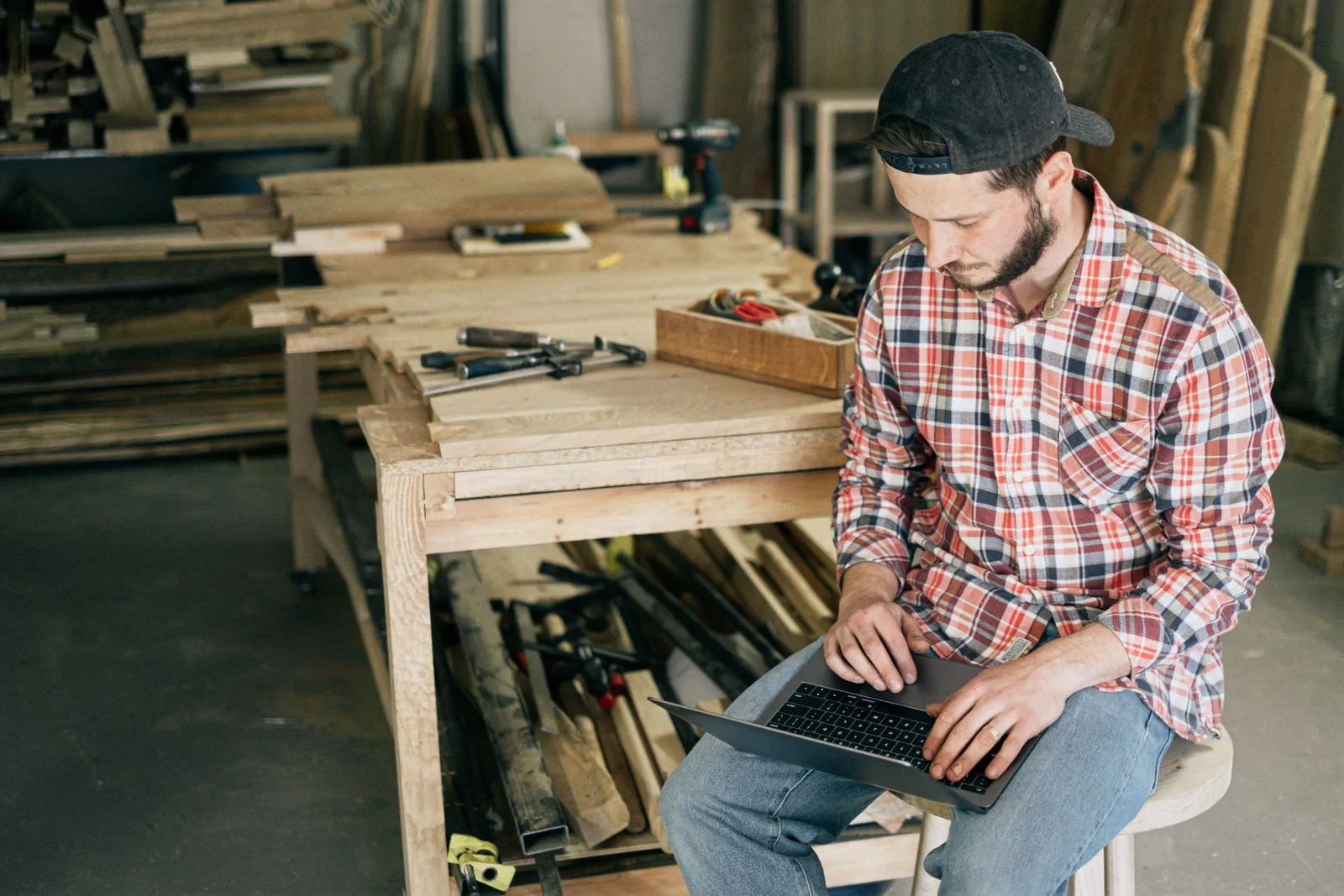 A small-business owner in his woodworking shop, sorting out his business on a laptop