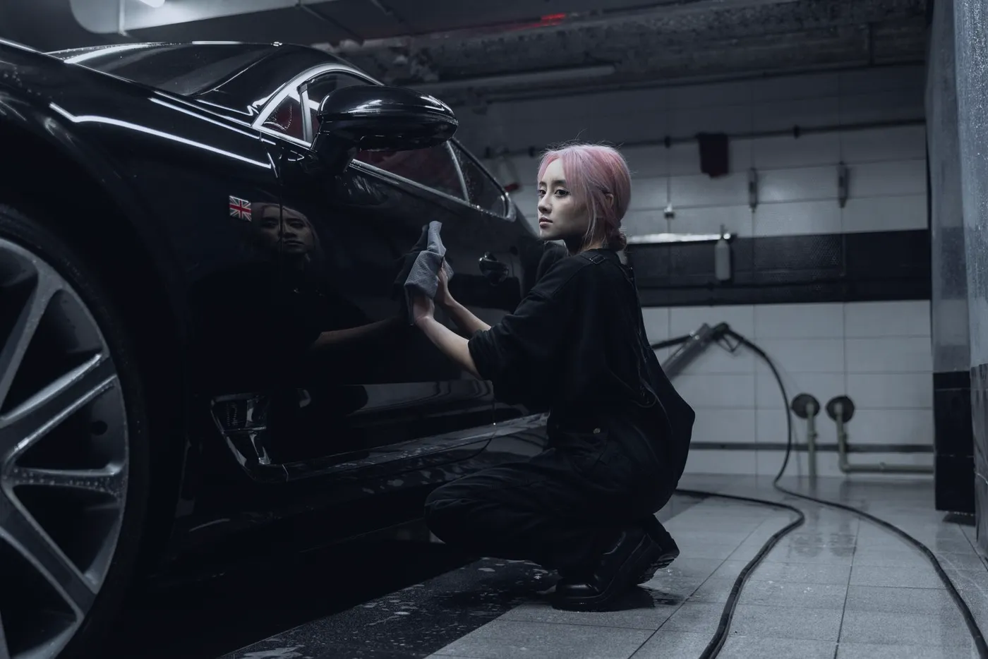 A detailer hand-finishing a black car in a detailing shop