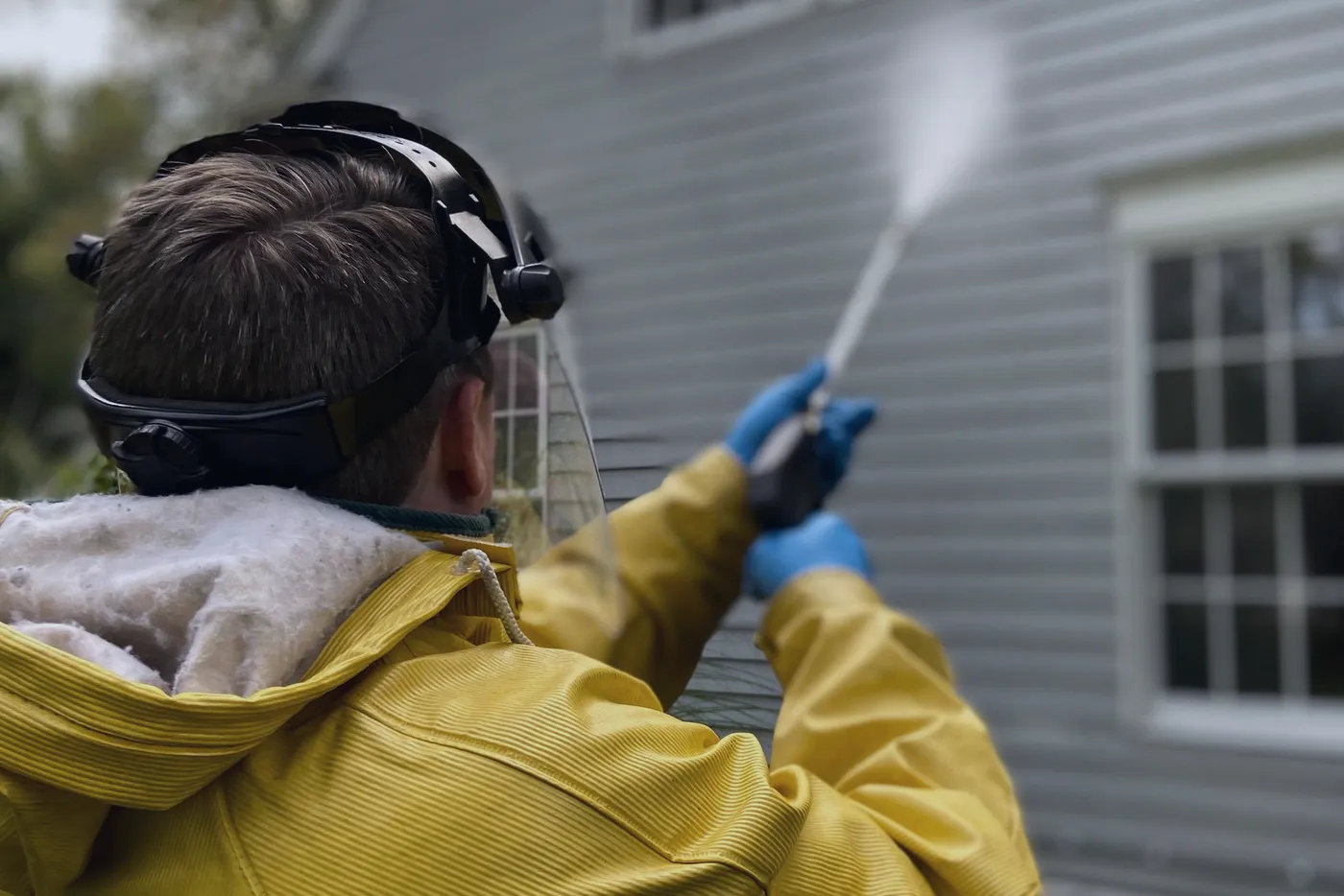 A pressure washer cleaning the siding of a house