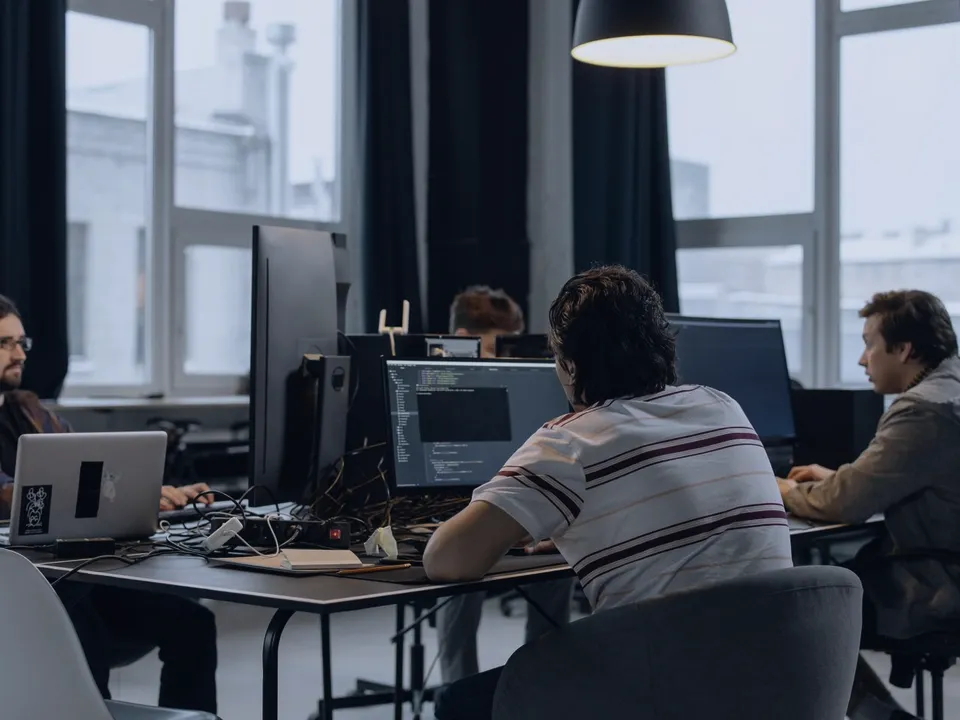 A development team at work in an office, code on the screens